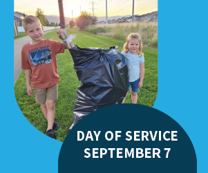 2 children holding a full black garbage bag 