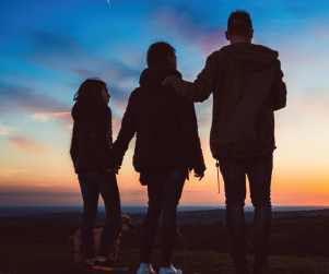 Three silhouettes looking at a sunset
