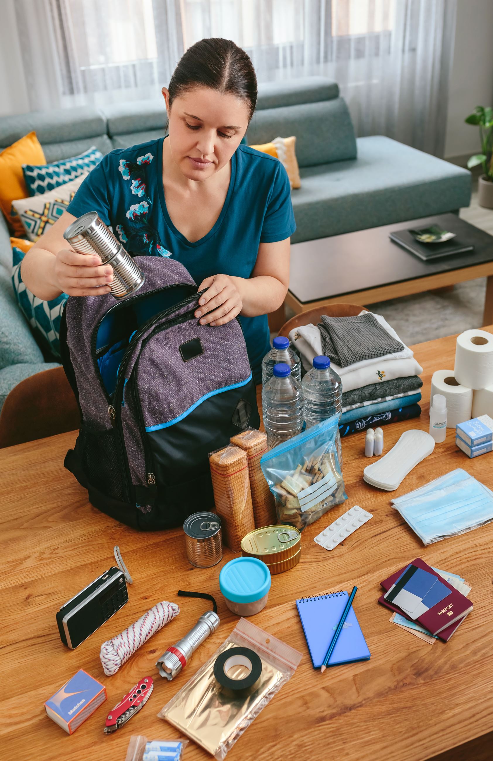 Woman filling backpack with emergency preparedness items