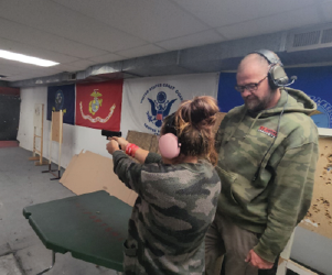 Student firing a gun while instructor looks on